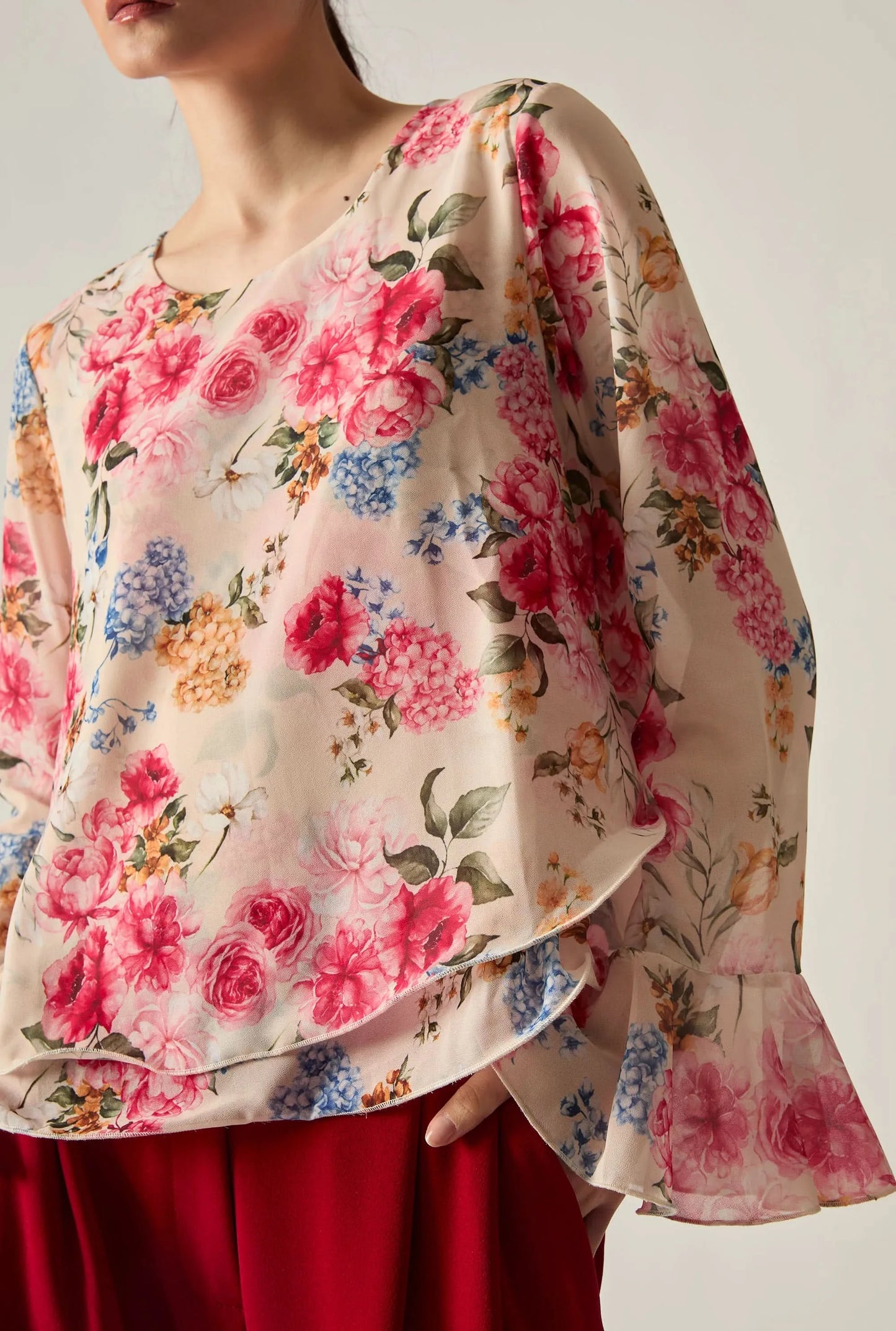 Close‑up of the bell sleeve on the floral printed blouse against a soft beige background.
